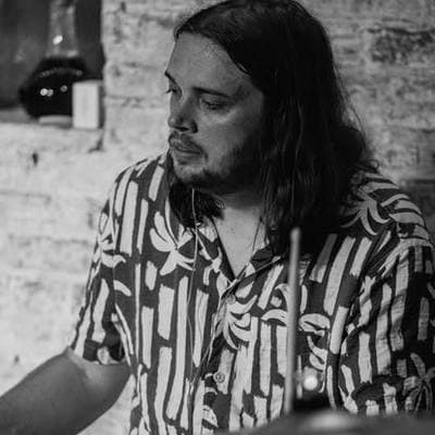 Black and white: a long-haired, bearded musician looking down mid-song.