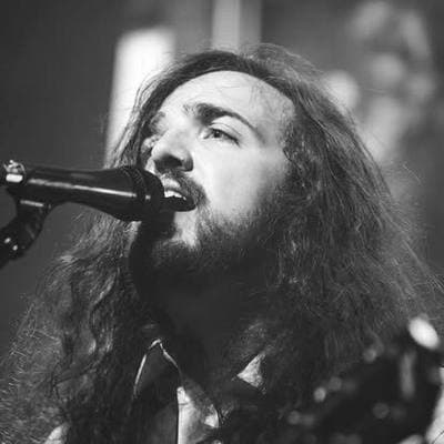 Black and white: a long-haired singer mid-song at the microphone.
