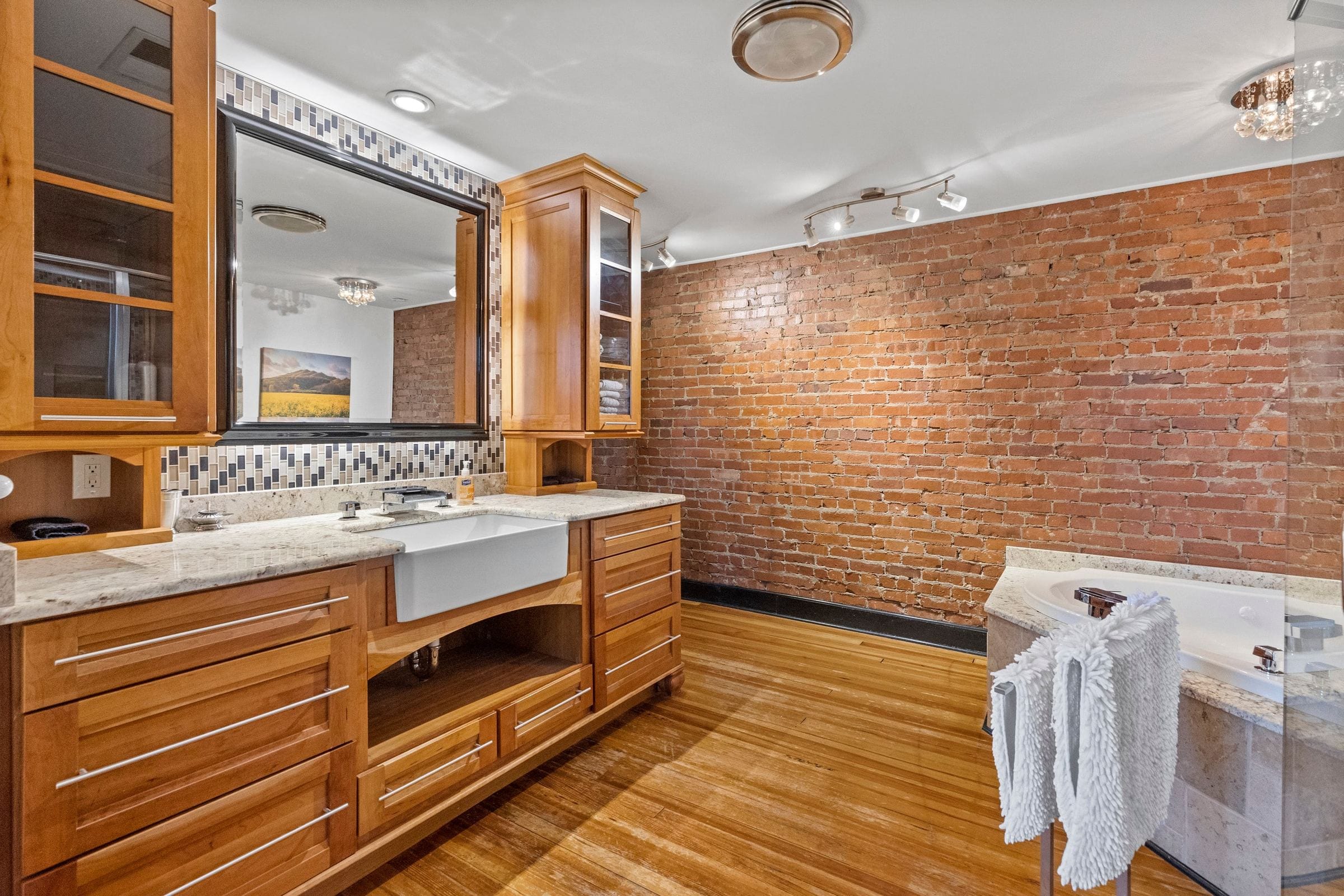 The bathroom vanity: a farmhouse sink, wood cabinets and exposed brick.