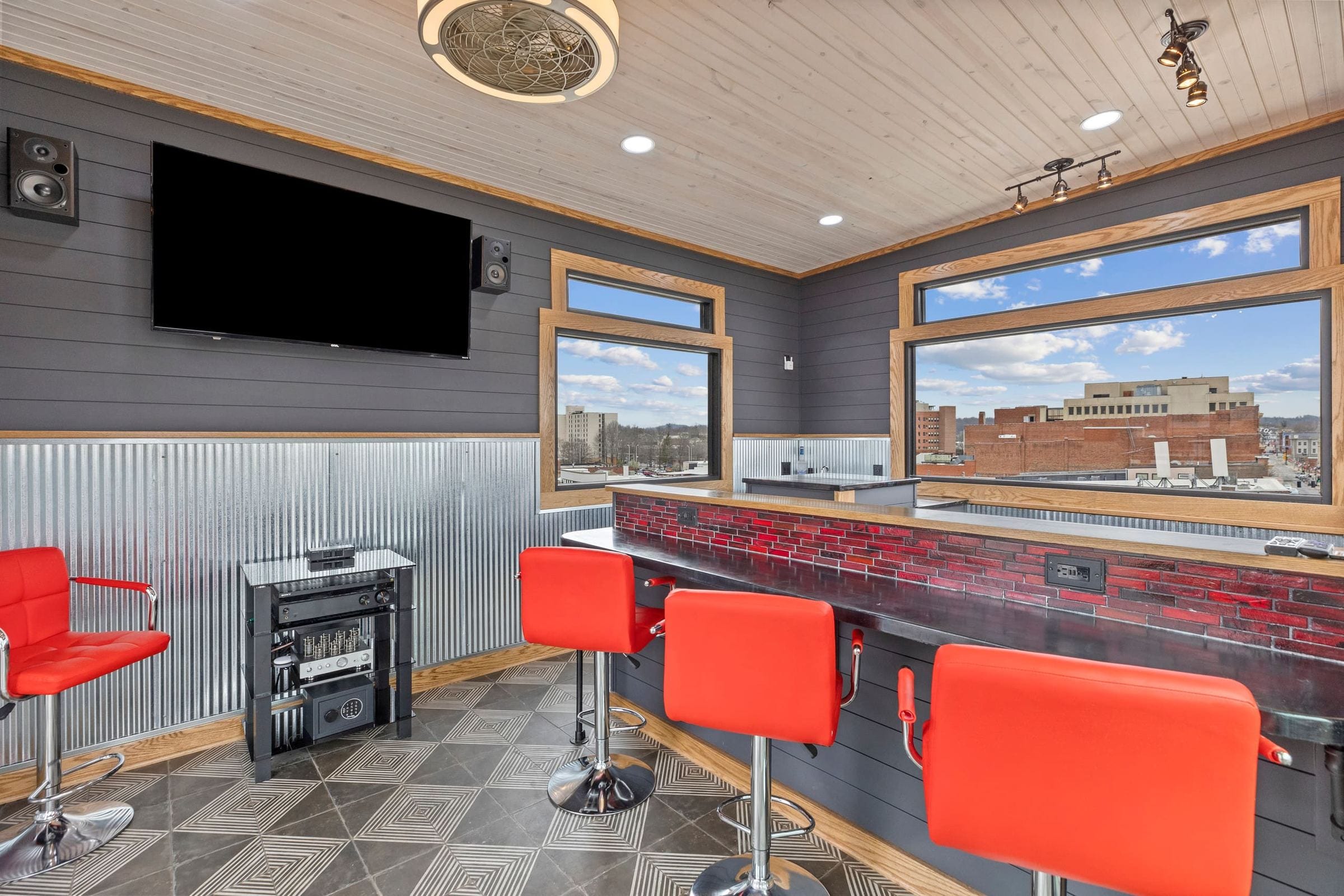 The penthouse bar and its TV, with red stools along the counter.