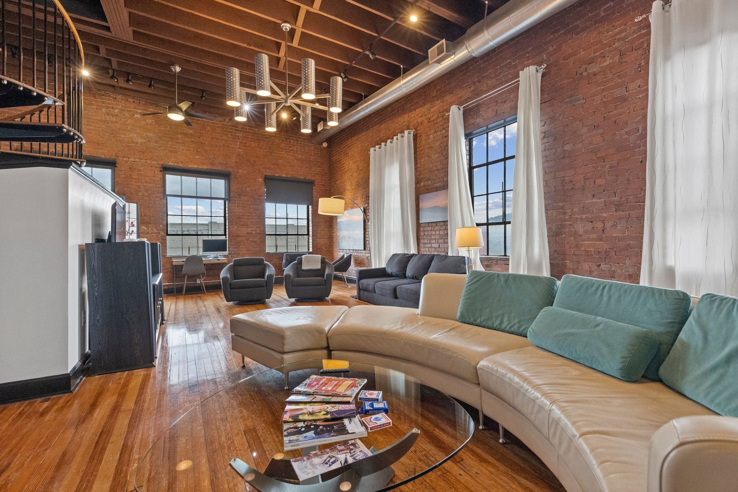 The curved sofa beneath the tall windows.