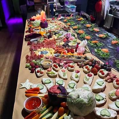 A long catered grazing table of charcuterie, fruit and finger food.